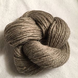 Könnte beinhalten: Ein Knäuel braunes Garn aus Naturfasern, das verknotet ist und zum Stricken oder Häkeln bereit ist.