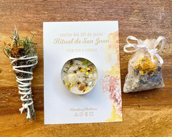 May include: An arrangement of spiritual items on a wooden surface. It includes a bundle of dried herbs wrapped in white string, a small candle with crystals and gold stars, a sachet of dried flowers, and a card with text in Spanish.