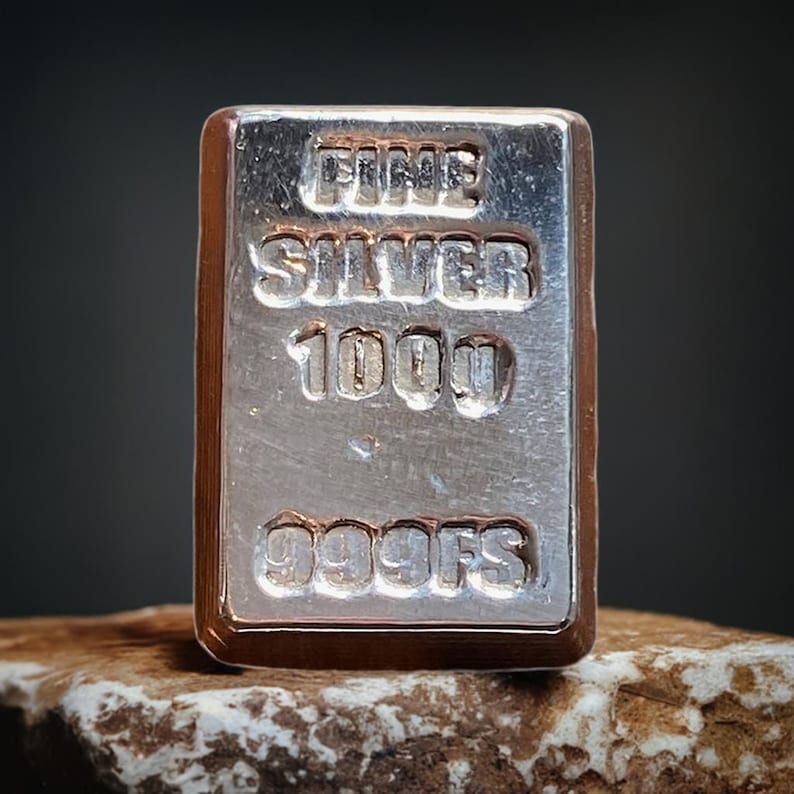 Pode incluir: Uma barra de prata com a inscri&ccedil;&atilde;o "FINE SILVER 1000 999FS".