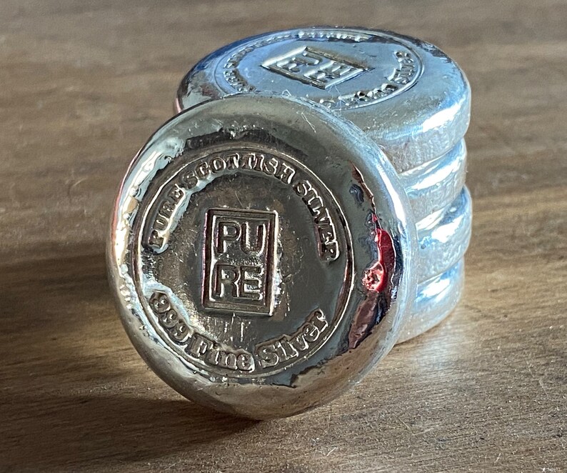 Puede incluir: Pila de cuatro barras de plata con las palabras "Pure Scottish Silver 999 Fine Silver" y "PURE" en relieve en la barra superior.