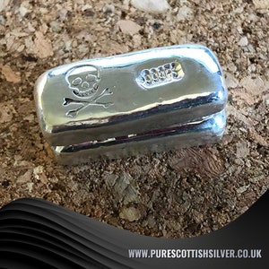 May include: A silver bar with a skull and crossbones design and the text "999.9" on the side.