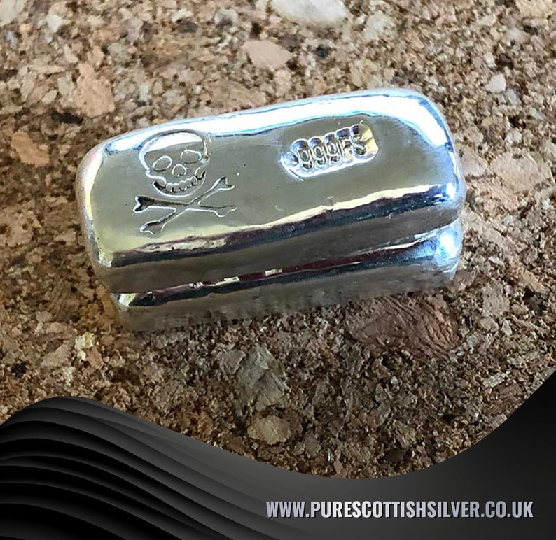 May include: A silver bar with a skull and crossbones design and the text "999.9" on the side.