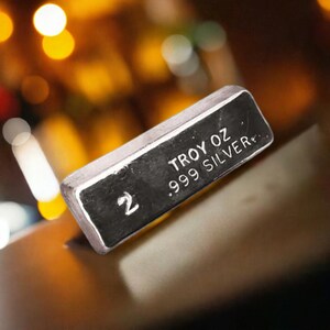 May include: A silver bar with the text "2 TROY OZ .999 SILVER" on it.