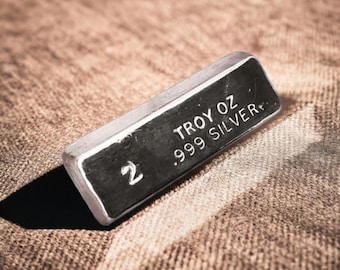 May include: A silver bar with the text "2 Troy oz .999 Silver" on it.