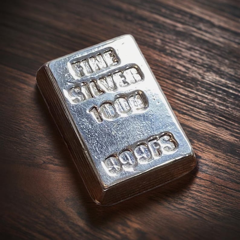 Pode incluir: Uma barra de prata com as palavras "Fine Silver 1000g 999FS" gravadas em relevo.