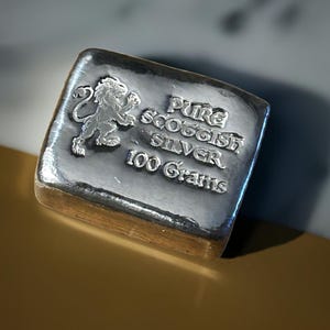 May include: A silver bar with a lion emblem and the text "Pure Scottish Silver 100 Grams".