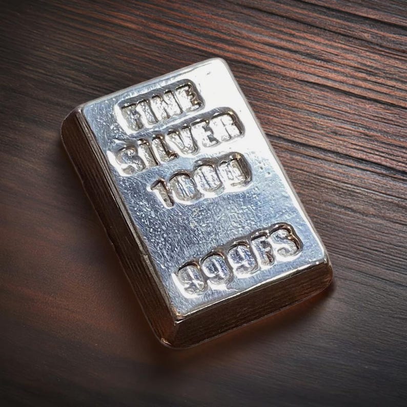 Pode incluir: Uma barra de prata com as palavras "FINE SILVER 1000g 999.9FS" gravadas nela.