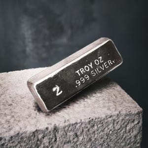 May include: A silver bar with the text "2 TROY OZ .999 SILVER" engraved on it.