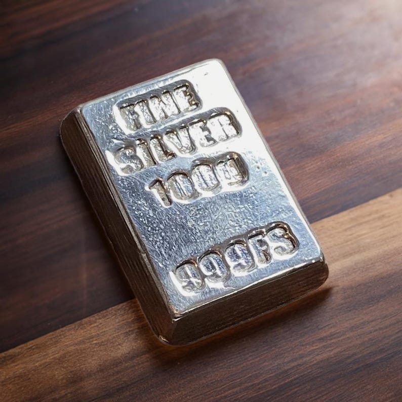 Pode incluir: Uma barra de prata com as palavras "FINE SILVER 1000g 999.9FS" gravadas em relevo.