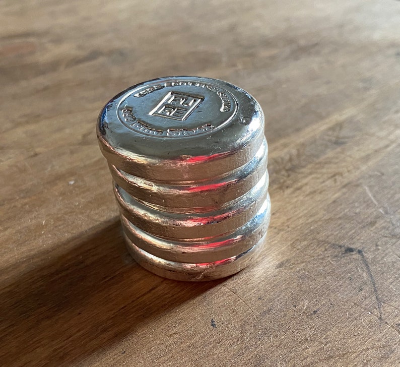 Puede incluir: Una pila de cuatro pesas de metal de color plateado con el texto "1 KG FINE SILVER 999" en la pesa superior.