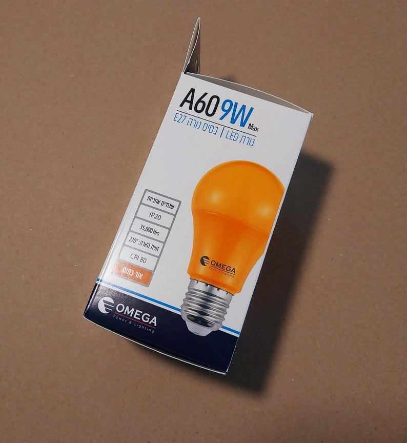 以下が含まれることがあります： 白と黒の箱に入ったオレンジ色のLED電球。箱には「A609W Max」と「OMEGA Power & Lighting」の文字があります。電球はE27ベースです。箱には電球の仕様も記載されています。