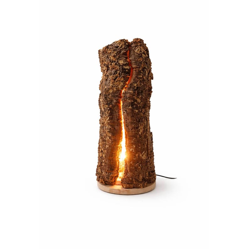 以下が含まれることがあります： 自然な質感の樹皮の外観を持つ装飾的なテーブルランプ。 ランプには、内部の光源からの温かくオレンジ色の光を明らかにする垂直の割れ目があります。 丸い明るい色の木製のベースにあり、黒い電源コードが付いています。 高さ約30cmです。