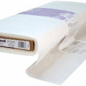 Könnte beinhalten: Eine Rolle weißes HeatnBond-Vliesofix, mittleres Gewicht, 18 Zoll mal 22 Zoll. Das Etikett lautet "HeatnBond Medium Weight 18" x 22" (45,7 cm x 55,9 cm) 100% Cotton Fusible Web. Hergestellt in den USA."
