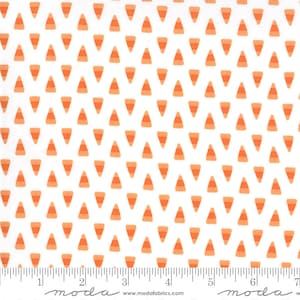 May include: White fabric with a repeating pattern of orange and peach candy corn shapes. The fabric is marked with a ruler in inches and the words "moda" and "www.modafabrics.com".