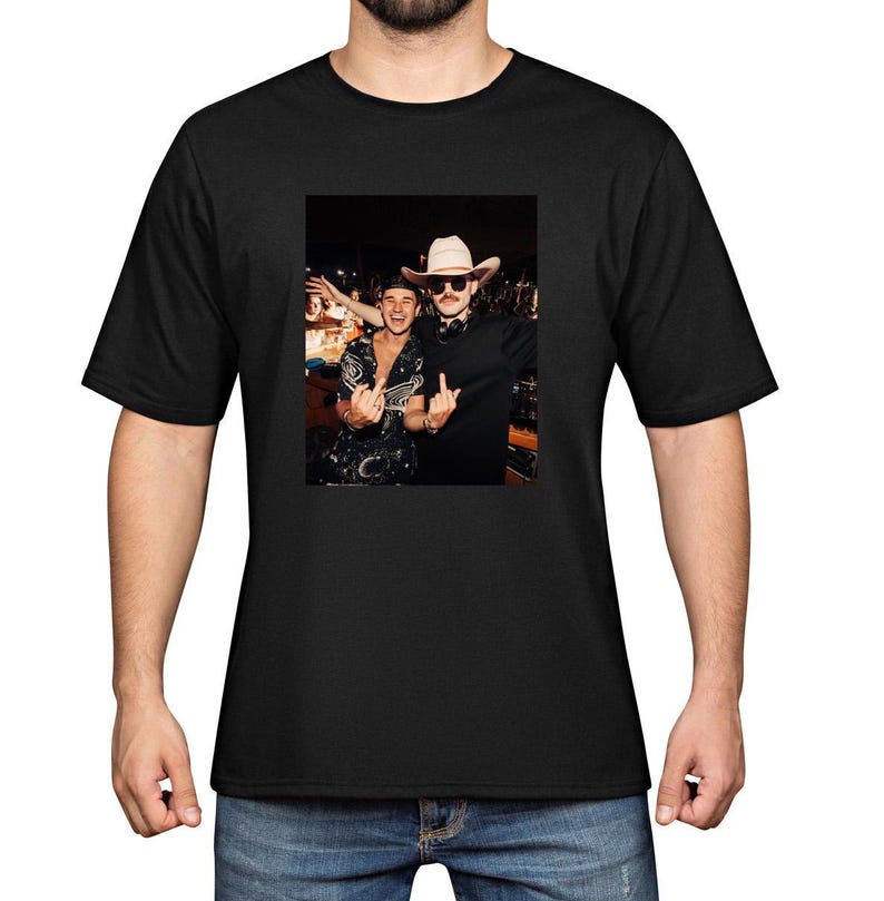 Puede incluir: Camiseta negra con una imagen impresa de dos personas. Una persona lleva un sombrero de vaquero y gafas de sol, la otra una camisa estampada. Ambos gesticulan con las manos. La camiseta est&aacute; hecha de un material suave y c&oacute;modo.