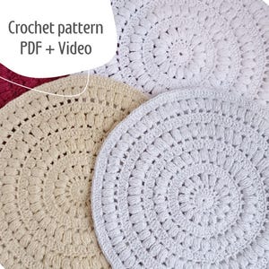 Könnte beinhalten: Drei runde Häkel-Platzsets in Weiß, Beige und Creme. Die Platzsets haben ein strukturiertes, kreisförmiges Muster.