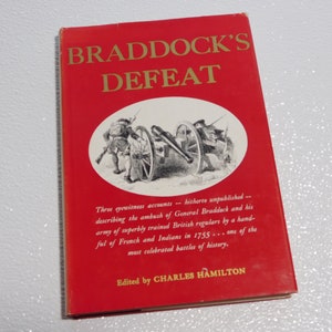 May include: A red book titled "Braddock's Defeat" with a black and white illustration of soldiers and a cannon on the front cover. The book is edited by Charles Hamilton and describes the ambush of General Braddock and his army by French and Indians in 1755.