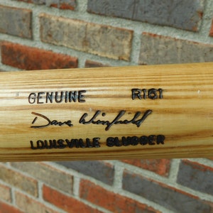 May include: A wooden baseball bat with the text "GENUINE", "R161", "Dave Winfield", and "LOUISVILLE SLUGGER" engraved on it.