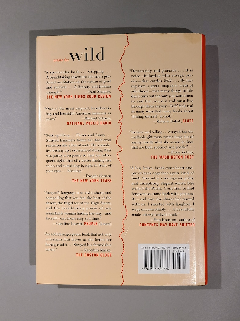 May include: Book cover for "Wild" by Cheryl Strayed. The cover features a red, white, and blue color scheme with a stylized image of a mountain range. The title "Wild" is in large, white letters. The book is a memoir about Strayed's journey on the Pacific Crest Trail.