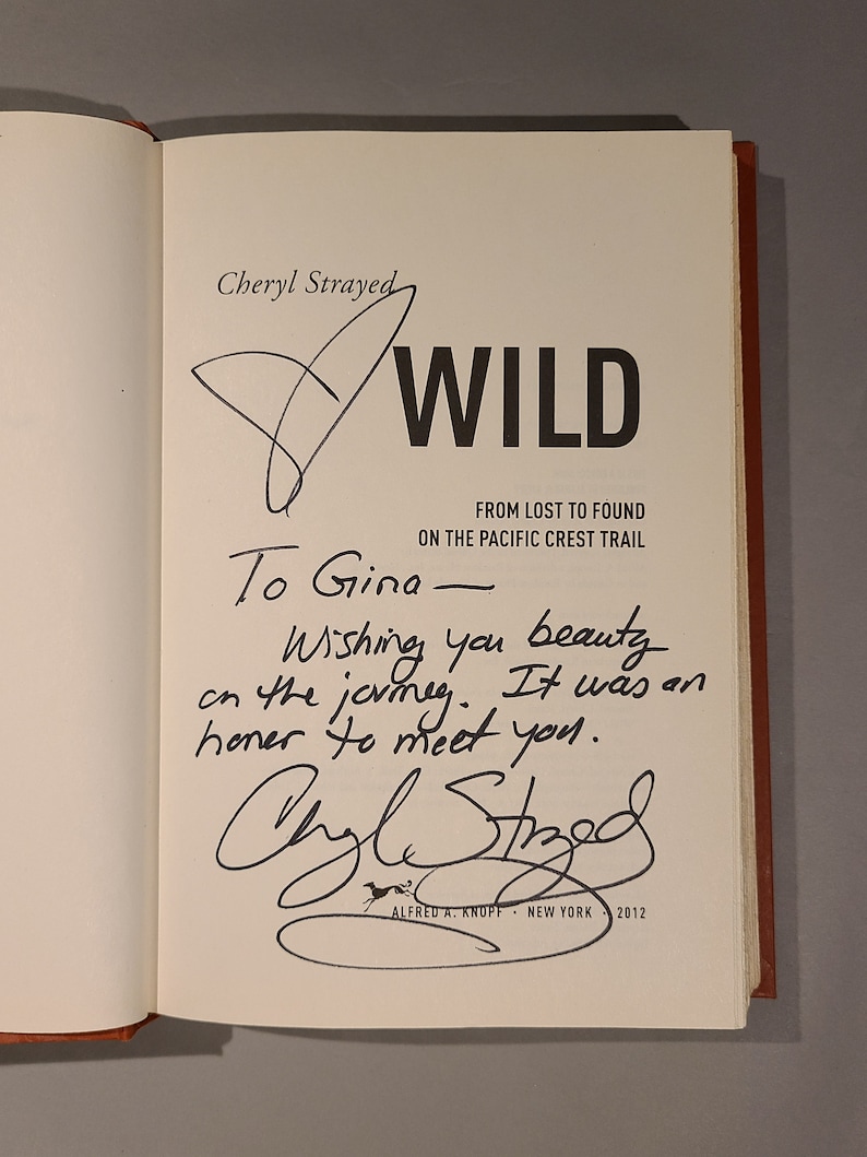 May include: A signed copy of the book "Wild: From Lost to Found on the Pacific Crest Trail" by Cheryl Strayed. The inscription reads "To Gina - Wishing you beauty on the journey. It was an honor to meet you."