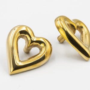 May include: Two gold heart-shaped door knobs with a smooth, polished finish.