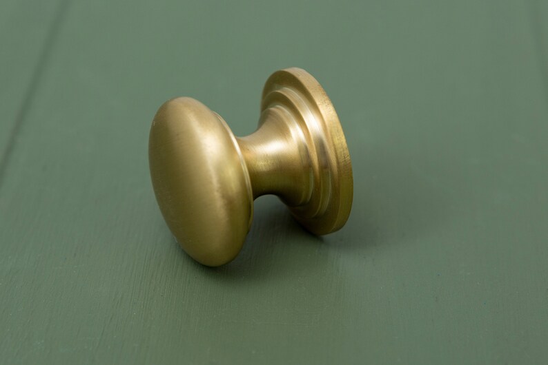 May include: A gold-toned cabinet knob with a round, slightly domed top and a fluted base.