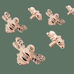 Può includere: Sei pomelli per mobili a forma di ape in oro rosa. Il design dell'ape è dettagliato e realistico, con ali, zampe e antenne.