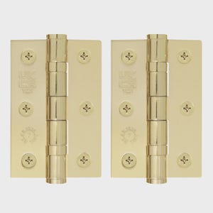 May include: Two polished brass door hinges featuring a central barrel and three screw holes on each side. The metal plates are stamped with the text UKCA 1121 and BS EN 1935 7 2002. Each hinge includes three flat-head screws installed in the plates.
