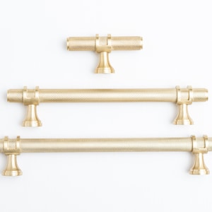 Può includere: Tre maniglie per armadi in metallo dorato con finitura testurizzata. Le maniglie sono di dimensioni diverse.