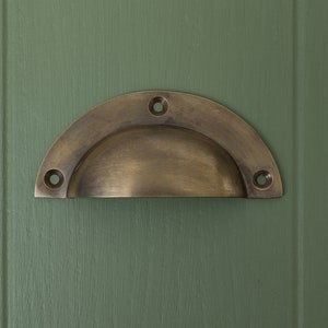 May include: A half-round brass cabinet pull with four screw holes.