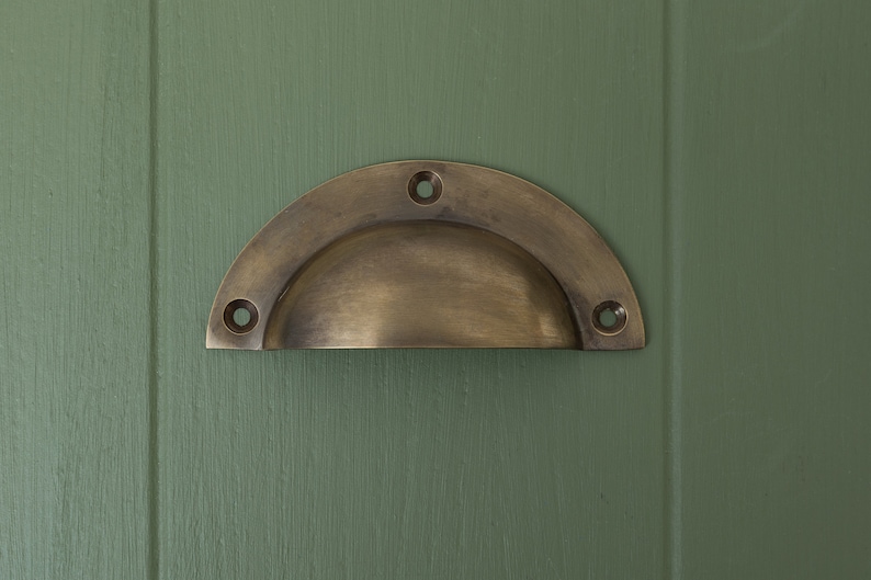 May include: A half-round brass cabinet pull with four screw holes.