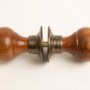 May include: A wooden door knob with a brass finish. The knob is round and has a smooth surface. The brass finish is polished and shiny.