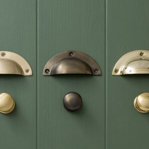 May include: Three sets of cabinet hardware in different finishes: polished brass, satin brass, and antique brass. Each set includes a cup pull and a knob.