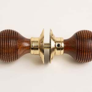 May include: A pair of brown wooden door knobs with a brass centre and a ribbed design.