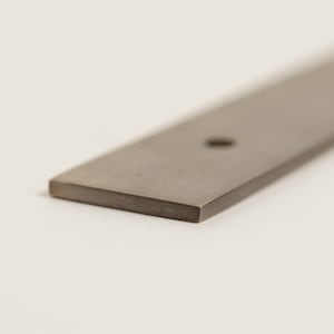 May include: A long, rectangular metal bar with a single hole drilled through the centre. The bar has a brushed finish and is a light grey colour.