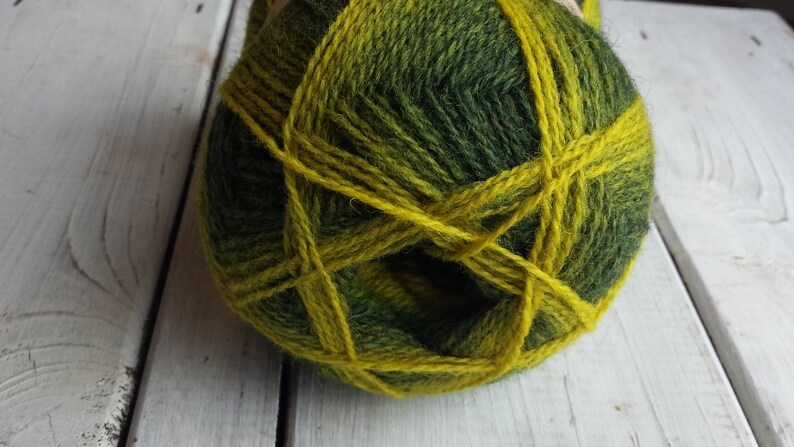 May include: A ball of green and yellow yarn with a variegated pattern. The yarn is wound into a ball shape and is ready for knitting or crocheting.