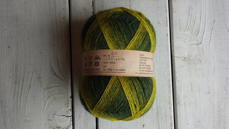 May include: A skein of green and yellow yarn with a label that reads "art. nr. EK LBC g 10g wool 100% 8/2 ca 100g ca 400m Kaun Oddernesvej 13 7323 Give Denmark tel +45 75190227 fax +45 75190228 e-mail kaun@kaun.dk www.kaun.dk"