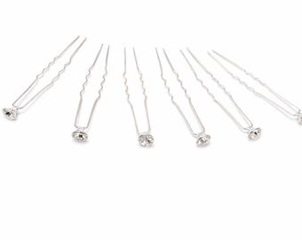 May include: Silver hair pins with a wavy design. Each pin has a small, clear rhinestone at the base. The pins are arranged in a semi-circle against a white background, suitable for bridal or formal hairstyles.