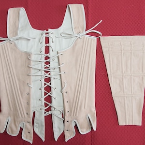 Puede incluir: Un cors&eacute; crema y rubor con un panel separado a juego. El cors&eacute; presenta un frente con cordones, tirantes y un dise&ntilde;o estructurado. El panel tiene una serie de l&iacute;neas cosidas verticales y horizontales.