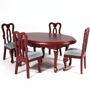 Puede incluir: Un juego de comedor de madera en miniatura con una mesa ovalada de caoba y cuatro sillas. Las sillas tienen un diseño de respaldo tallado y están tapizadas en tela gris claro.