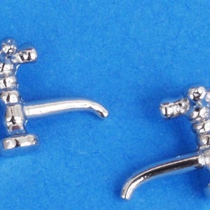Pode incluir: Dois misturadores miniatura prateados com um design detalhado. Os misturadores têm um bico curvo e uma base redonda.