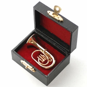 Puede incluir: Un eufonio dorado en miniatura descansa dentro de un pequeño estuche negro con forro de terciopelo rojo. El estuche está abierto, revelando los detalles del instrumento. El estuche tiene cierres dorados y un cierre en forma de llave.