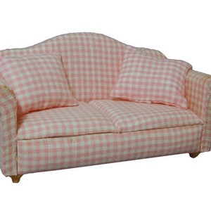 May include: A miniature two-seater sofa with a pink and white gingham pattern. The sofa has two matching cushions and curved armrests. The wooden legs are visible. This dollhouse furniture piece is ideal for a child's play set or a collector's display.