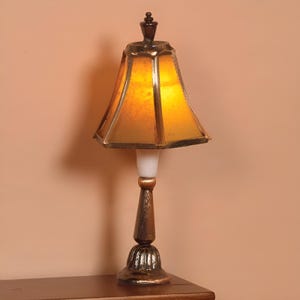May include: A gold table lamp with a yellow glass shade. The lamp has a decorative base and a finial on top.