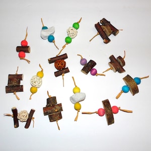 May include: Assortment of colorful wooden bird toys with beads, balls, and natural wood pieces. The toys are strung together with twine and are designed for small birds.