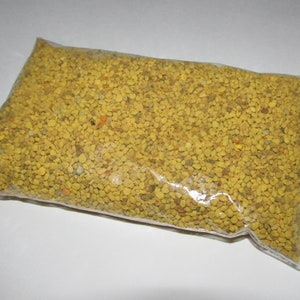 May include: A close-up of a clear plastic bag filled with yellow bee pollen granules.