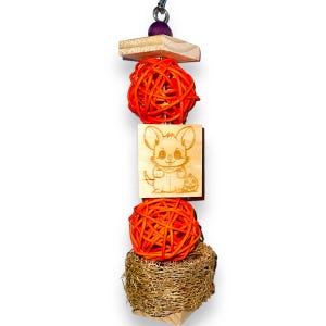 May include: A wooden toy for small pets features a hanging orange ball, a wooden block with a cartoon mouse and pumpkin, another orange ball, and a natural sisal rope.