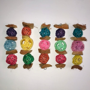 May include: A set of six colorful, woven bird toys. Each toy is made of natural materials and features a variety of colors and textures. The toys are strung together with a metal ring and are perfect for small birds to play with.
