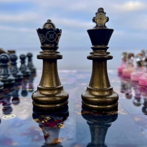 May include: Close-up of a chess set with a steampunk aesthetic. The queen and king pieces are in focus, with intricate gear-like details on their crowns. The pieces have a metallic bronze finish, reflecting on the board's surface. Other pieces are visible in the background.