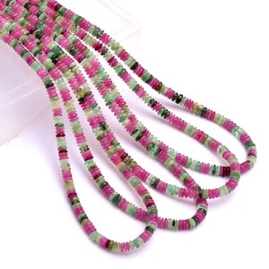 Op de afbeelding: Een streng roze en groene edelsteen kralen. De kralen zijn klein en rond en zijn geregen aan een dunne draad. De kralen zijn in een willekeurig patroon gerangschikt en creëren een mooi en kleurrijk effect.